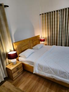 sypialnia z łóżkiem i nocną szafką z 2 lampami w obiekcie Laspa Cottage, Bhimtal w mieście Bhimtal