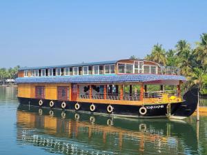 a boat on the water with a building on it at Sukūn Houseboats in Kannur