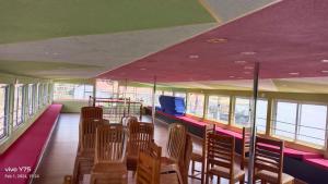 a room with chairs and tables and windows at Sukūn Houseboats in Kannur