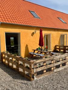 a building with tables and an umbrella in front of it at Ellens Have, Lejlighed Asta in Ebeltoft