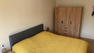 a bedroom with a yellow bed and a wooden cabinet at Logement 1860 in Nieuw-Amsterdam