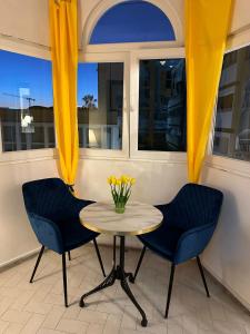 duas cadeiras e uma mesa com um vaso de flores amarelas em Appartment Avenue Hassan II em Agadir