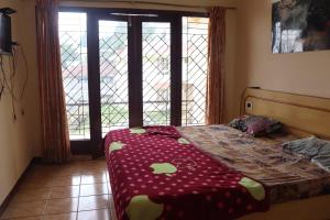 1 dormitorio con 1 cama con edredón rojo y ventanas en Trio heaven homestay, en Kodaikanal