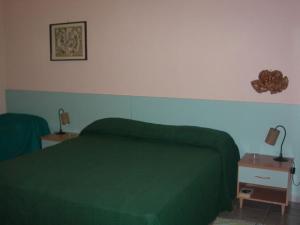 a bedroom with a green bed and a night stand at Villa La Spada in Taormina
