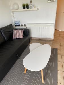 a living room with a black couch and a white table at Genieten aan zee in De Haan in De Haan