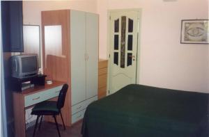a bedroom with a bed and a desk with a television at Villa La Spada in Taormina