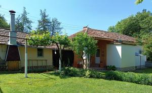 a small yellow and white house with a yard at Divna Guest House in Krushuna