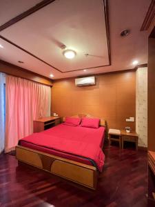 a bedroom with a bed with a red bedspread at Grand Diamond Condo Suites in Bangkok