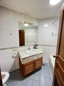 a bathroom with a sink and a toilet and a mirror at Grand Diamond Condo Suites in Bangkok