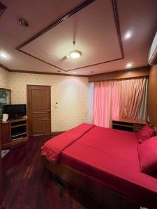 a bedroom with a red bed and a television at Grand Diamond Condo Suites in Bangkok