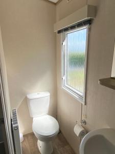 a small bathroom with a toilet and a window at Stunning Caravan on Swanage Bay View Holiday Park in Swanage