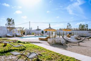 a yard with a pool with benches and umbrellas at Villa Madame Babouche, chambre Hayda, SdB privative in Oulad el Madani +6 photos