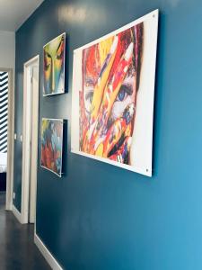 een muur met drie schilderijen aan een blauwe muur bij Maison 120m - Animaux acceptés in Sainte-Cécile-les-Vignes