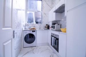 a white kitchen with a washing machine in it at Selfridges Skyline Suite Located Next to Bond Street in London