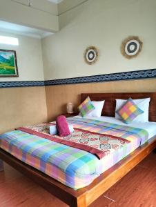 een bed met een kleurrijk dekbed en kussens erop bij Nami House in Ubud