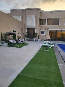 a building with a yard with green grass and an umbrella at La Seema sea view chalet in Madaba