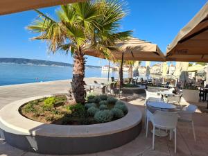 a patio with tables and chairs and a palm tree at Blanca in Kaštela