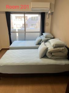 two beds in a room with a window at SkyHotel Ryogoku 駅徒歩4分 in Tokyo