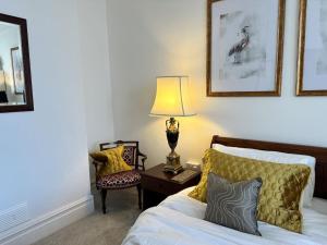 a bedroom with a bed with a lamp and a chair at Pebbles by the sea in Criccieth