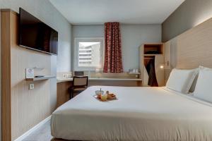 um quarto de hotel com uma cama grande e uma janela em Kyriad Marseille Palais Des Congrès – Vélodrome em Marselha