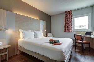 um quarto de hotel com uma cama, uma secretária e uma janela em Kyriad Marseille Palais Des Congrès – Vélodrome em Marselha