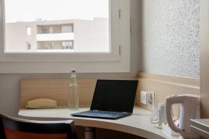 een laptop op een bureau met een fles erop bij Kyriad Marseille Palais Des Congrès – Vélodrome in Marseille