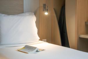 - un lit avec un oreiller et un journal dans l'établissement Kyriad Marseille Palais Des Congrès – Vélodrome, à Marseille