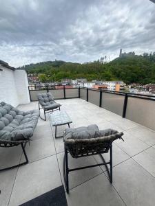 uma varanda com cadeiras e mesas num telhado em LiT LiVING: Luxury - Box Spring - große Terrasse - bbq - sagenhafte Aussicht em Weinheim