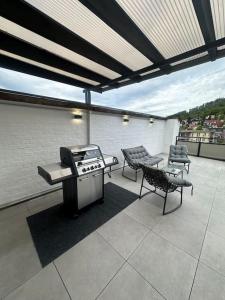 un patio con parrilla, 2 sillas y una mesa en LiT LiVING - Luxury - Box Spring - große Terrasse - bbq - sagenhafte Aussicht - Parken, en Weinheim