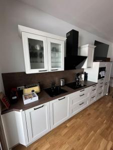 a kitchen with white cabinets and a black counter top at LiT LiVING: Luxury - Box Spring - große Terrasse - bbq - sagenhafte Aussicht in Weinheim