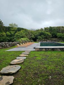 a pool with a row of rocks next to a park at Aldeia da Cuada in Faja Grande