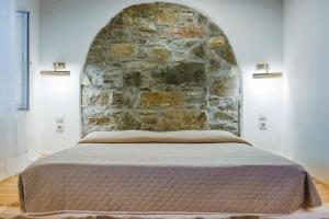 a bed in a room with a stone wall at Anesis Traditional Rhodian House in Kattavía