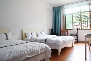 - une chambre avec 2 lits et une fenêtre dans l'établissement Longyan Yongding Tulou Mengtian Inn, à Yongding