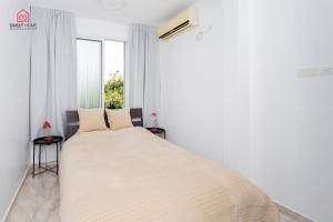 ein weißes Schlafzimmer mit einem Bett und einem Fenster in der Unterkunft Family App in Netanya in Netanya