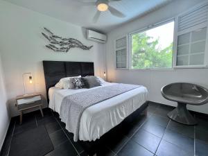 a bedroom with a bed and a table and a window at BEACHFRONT Diamond Rock - Guest Suite with breakfast area OR Entire Apartment in Le Diamant