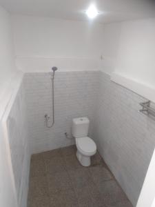 uma casa de banho branca com um WC e um chuveiro em Rain homestay em Selong