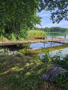 un puente de madera sobre un cuerpo de agua en Dom letniskowy przy lesie nad jeziorem en Rogowo