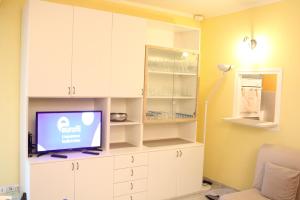 een woonkamer met een tv en witte kasten bij Victoria Palace in Menton