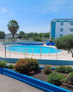 una gran piscina con árboles y un edificio en Escapade Côtière au Grau du Roi, en Le Grau-du-Roi