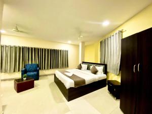 a bedroom with a bed and a blue chair at Hotel Sky Park in Shamshabad