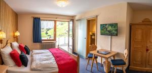Schlafzimmer mit einem Bett, einem Schreibtisch und einem Tisch in der Unterkunft Schwarzwald Hotel Wiedenerhof in Wieden