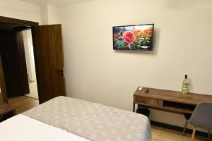een slaapkamer met een bed en een bureau en een televisie aan de muur bij Guest House LAZARA in Veliko Tŭrnovo