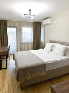 een slaapkamer met een groot wit bed en een bureau bij Guest House LAZARA in Veliko Tŭrnovo