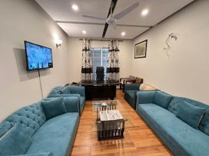 uma sala de estar com sofás azuis e uma televisão de ecrã plano em Family lodges em Islamabad