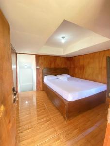 uma cama grande num quarto com piso em madeira em Rain homestay em Selong