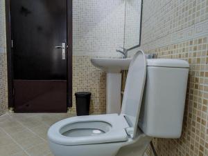 bagno con servizi igienici bianchi e lavandino di Comfort Bed Inn a Dubai