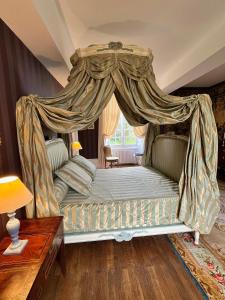 a bedroom with a canopy bed and a table at Château de Cadouzan in Saint-Dolay