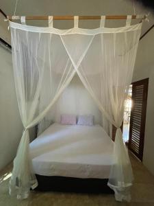 a bedroom with a bed with a canopy at Elephant House and Bungalows Gili Air in Gili Air