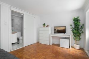 una sala de estar blanca con TV en un escritorio en Maria Pia Suite 4 com Terraço, en Oporto