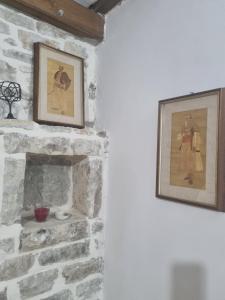una chimenea de piedra con dos cuadros en la pared en Villa Olive Old Qeparo, en Qeparo